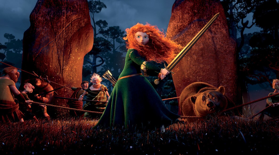 Merida, voiced by Kelly Macdonald, wielding a sword with other highlanders in the the background in the movie Brave