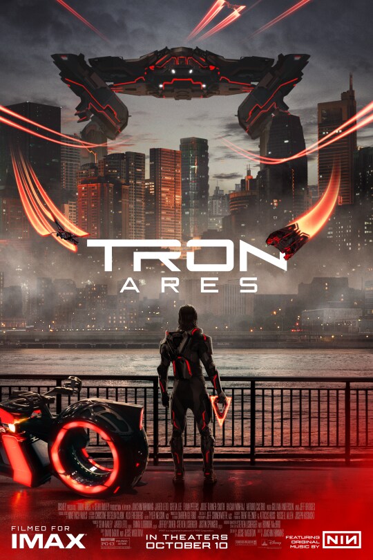 Image of a person standing next to a light cycle holding a disc while looking towards a large vehicle hovering over a body of water in front of a city. | Tron: Ares | Filmed for IMAX | Rated PG-13 | In theaters October 10 | Featuring original music by NIN | movie poster