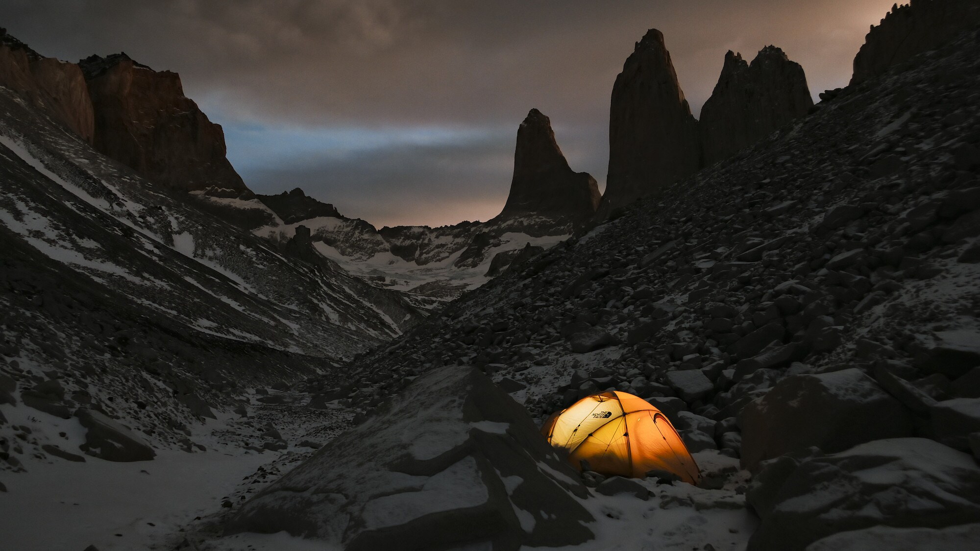 Night shot of a tent nestled between the rocks. National Geographic for Disney+/Keith Partridge)