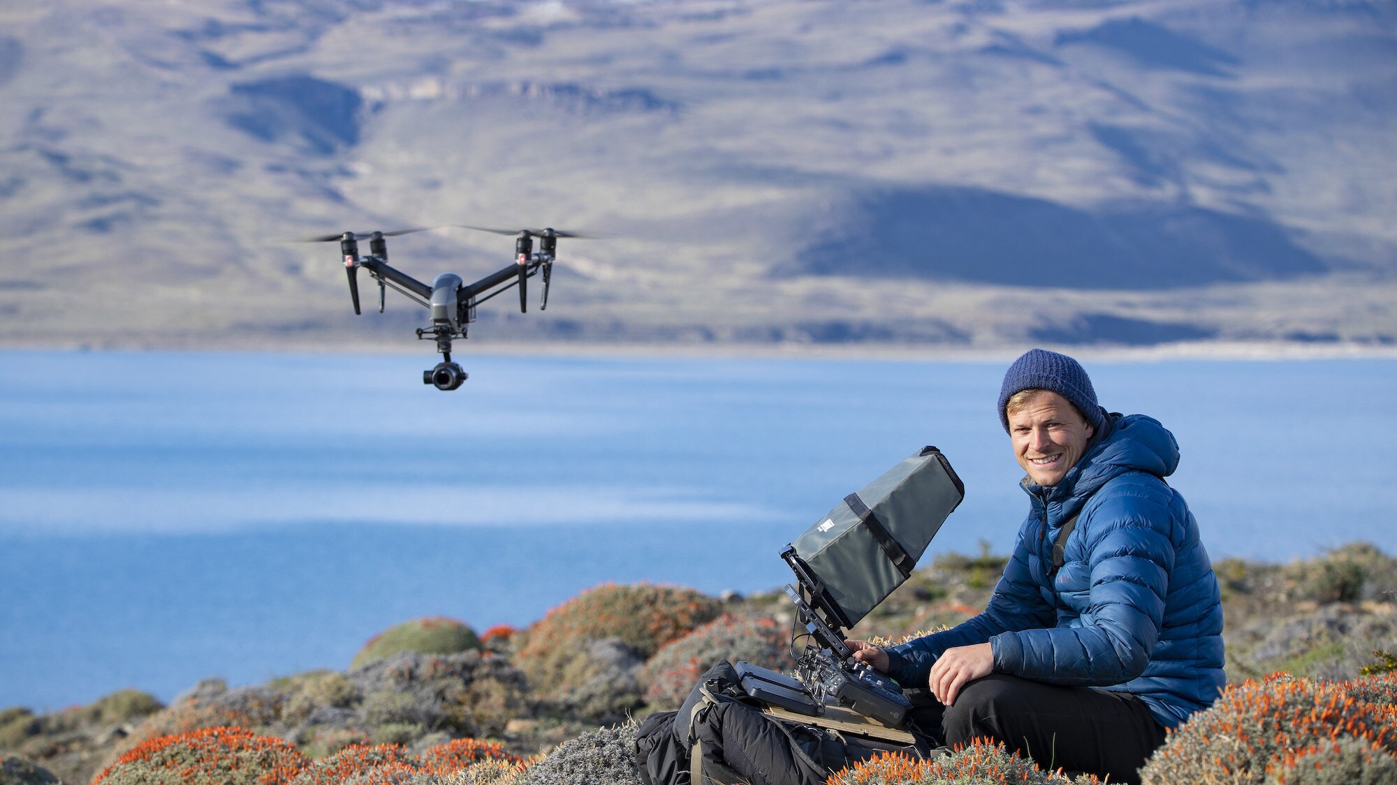 Bertie Gregory smiling at the camera and controlling the drone.  (National Geographic for Disney+/Anna Dimitriadis)