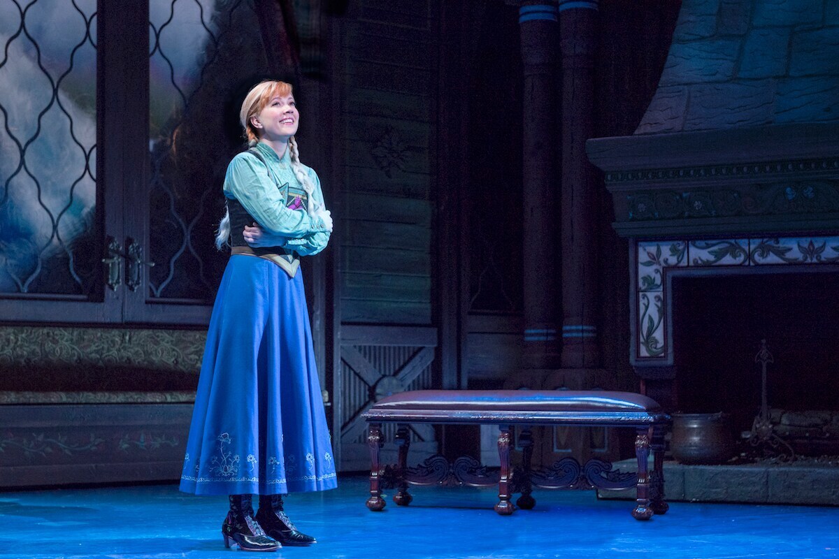 Anna from Frozen on Broadway standing on a stage in blue light. 