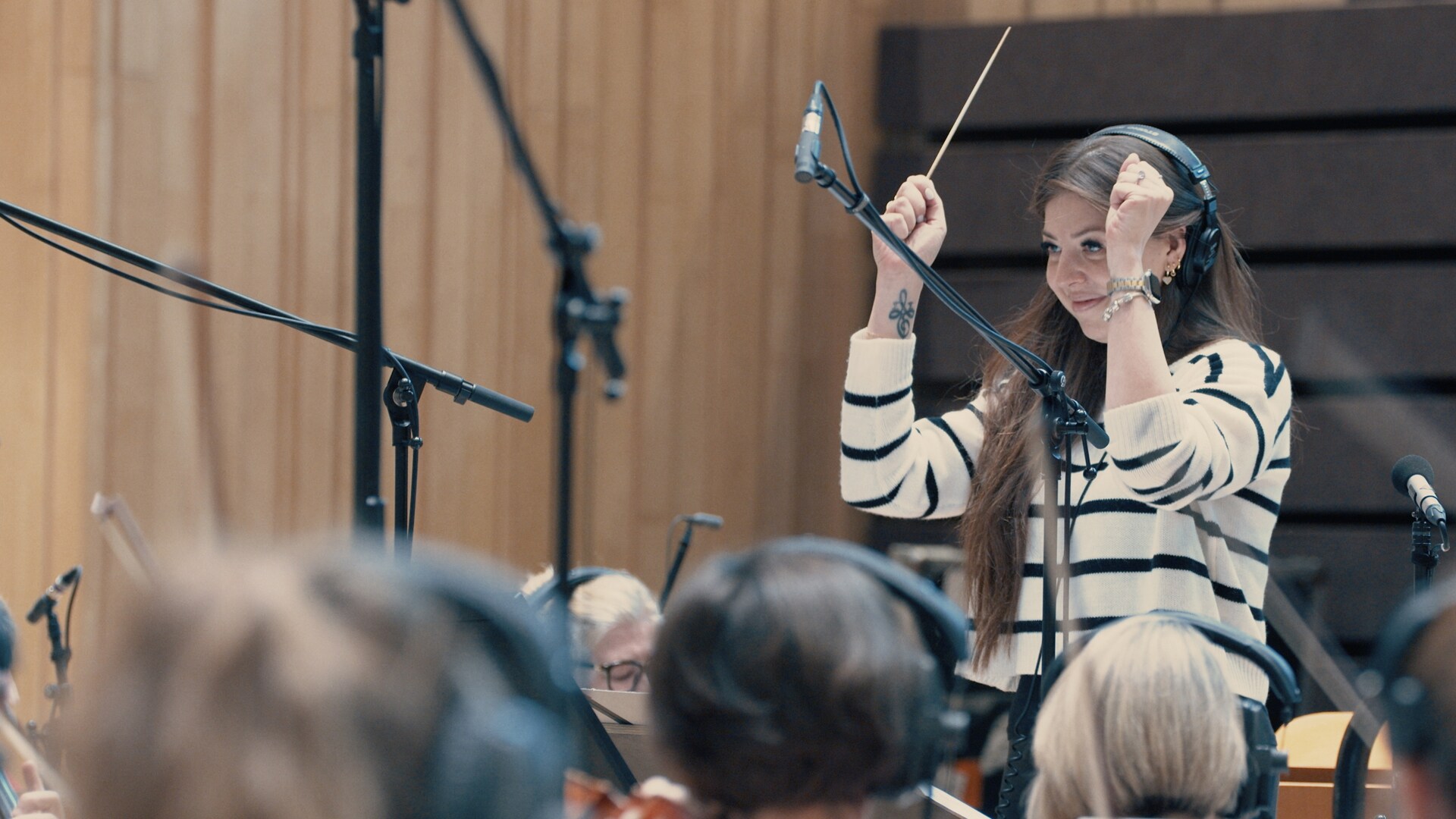 An image of composer Pinar Toprak conducting an orchestra.