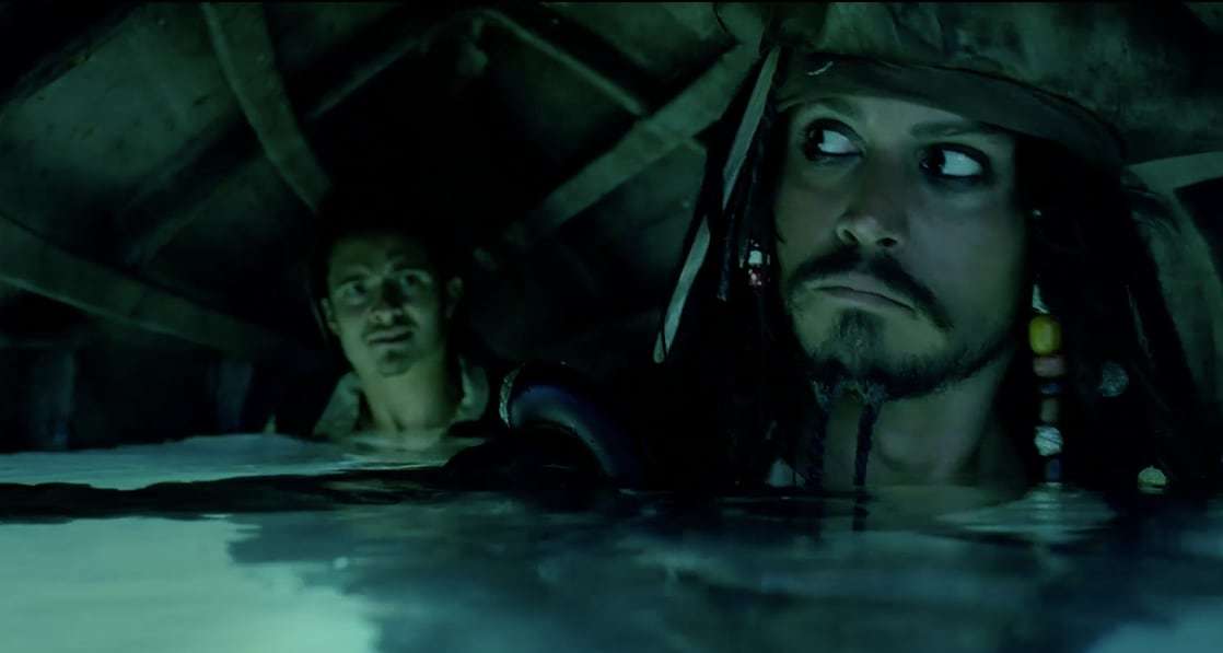 Actors Johnny Depp (Captain Jack) and Orlando Bloom (Will Turner) under a boat.