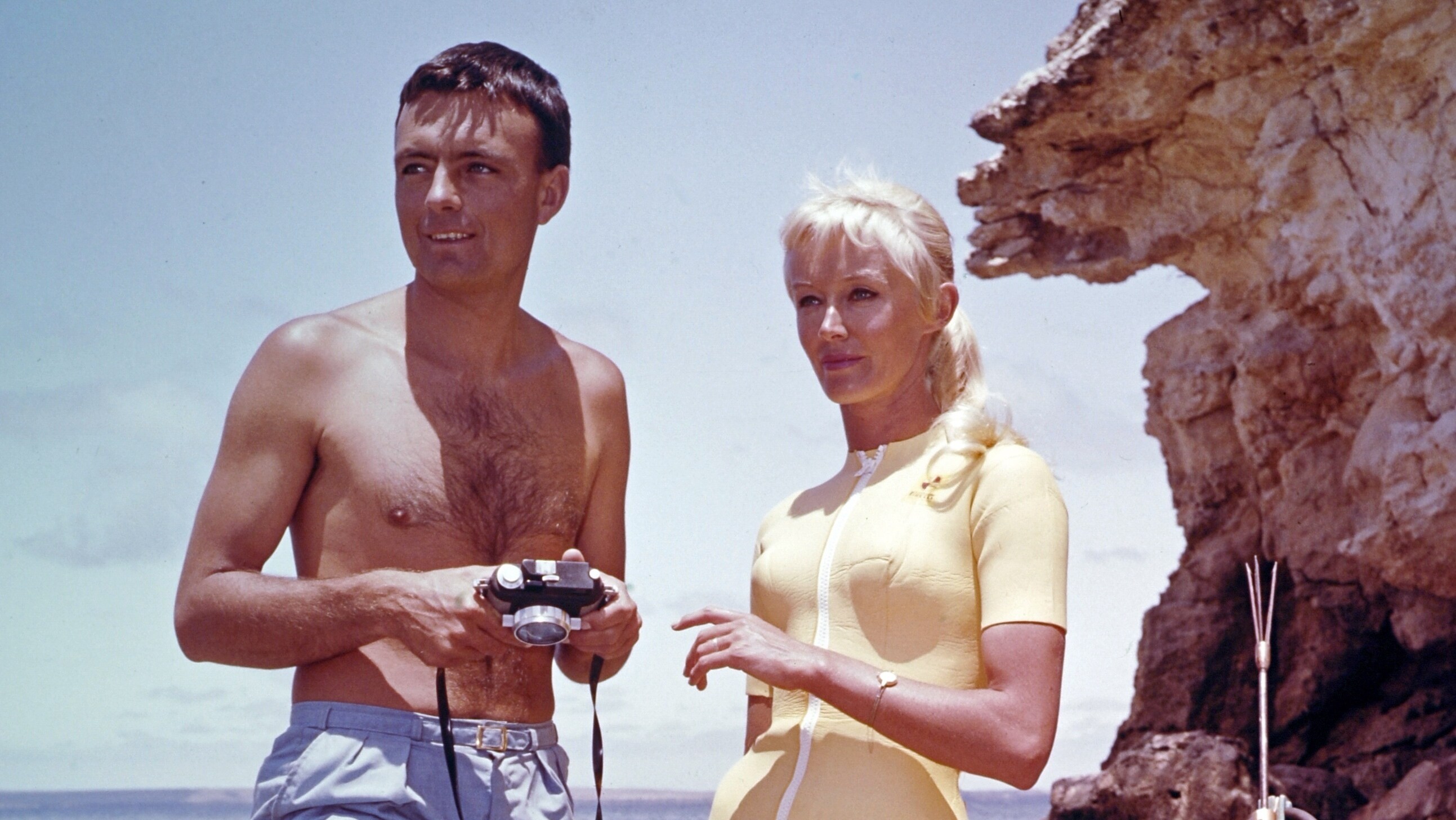 Ron & Valerie Taylor with spearfishing equipment standing on rocks in 1962. (photo credit: Ron & Valerie Taylor)