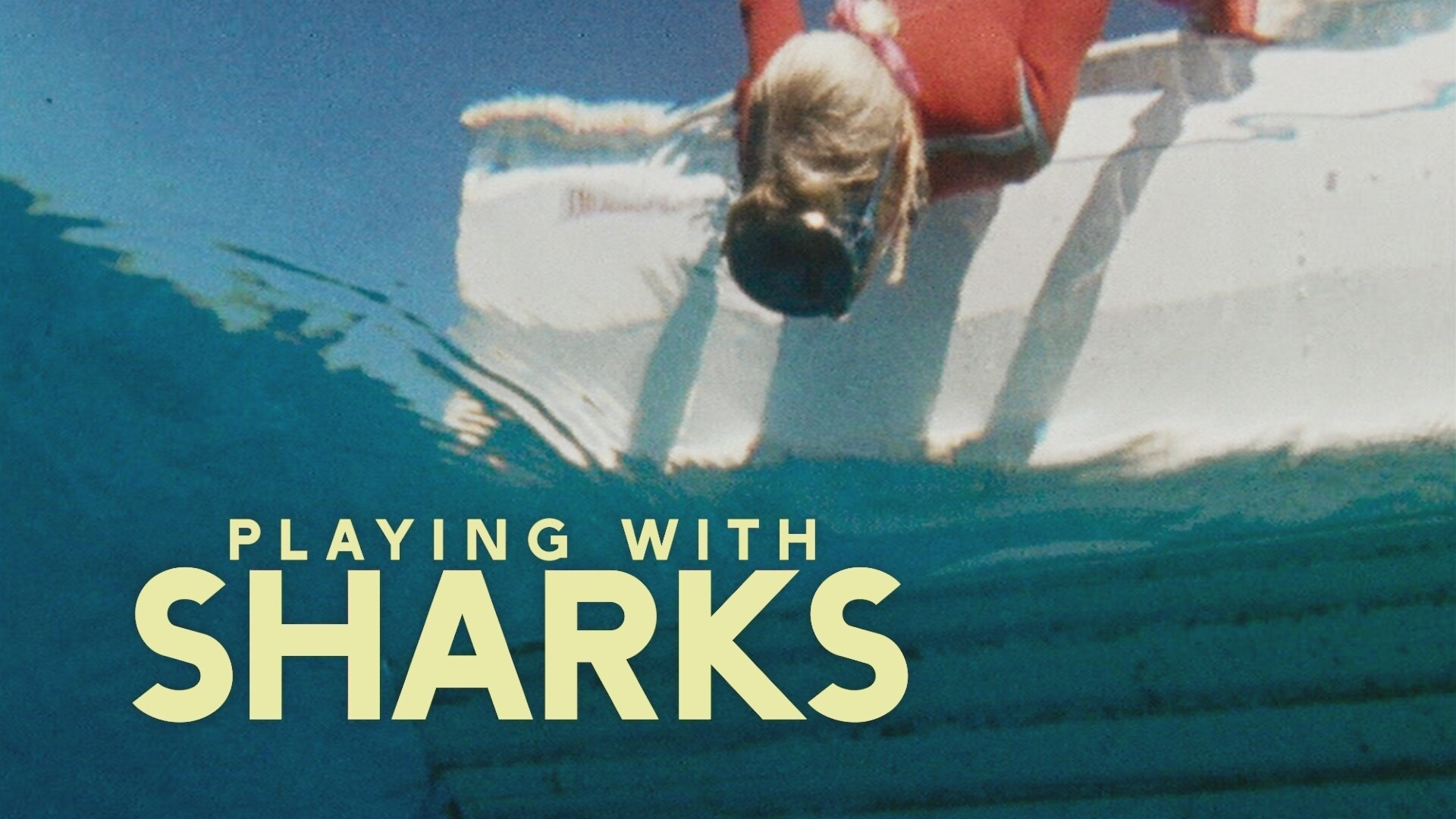 Valerie Taylor leaning over the boat looking into water in 1968. Shot from underwater.  (photo credit: Ron & Valerie Taylor)