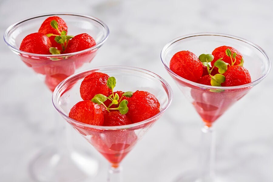 Image of plum-infused cherry tomatoes in three martini glasses