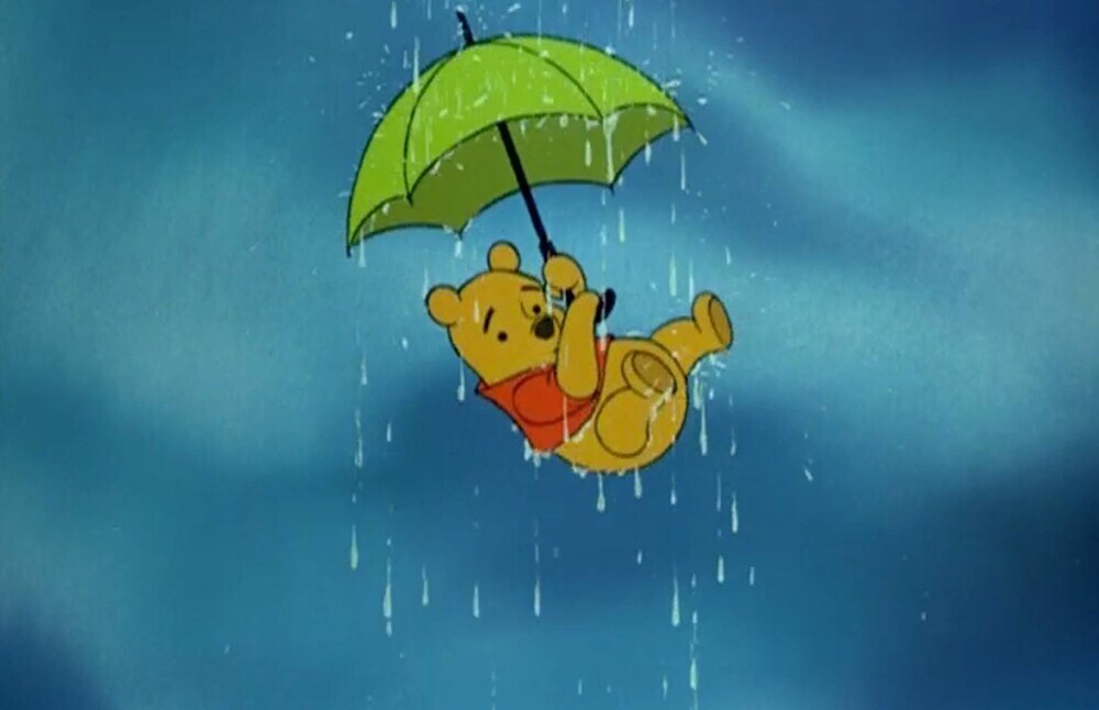 Winnie the Pooh in the air holding a green umbrella in the rain