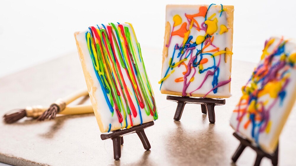 Three pop art cookies that have colorful abstract frosting art