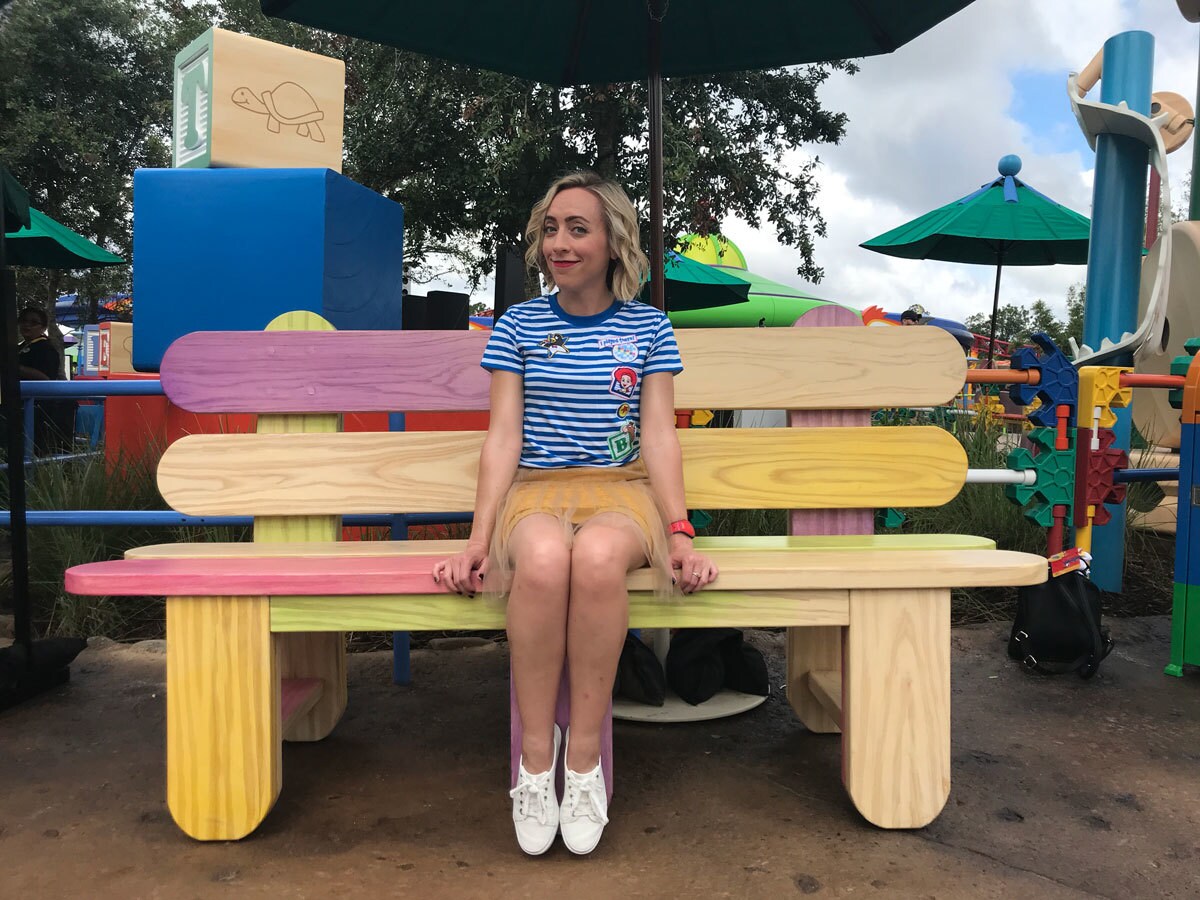 Oh My Disney Host Michelle Lema sitting on the Popsicle Stick Bench at Toy Story Land in Walt Disney World