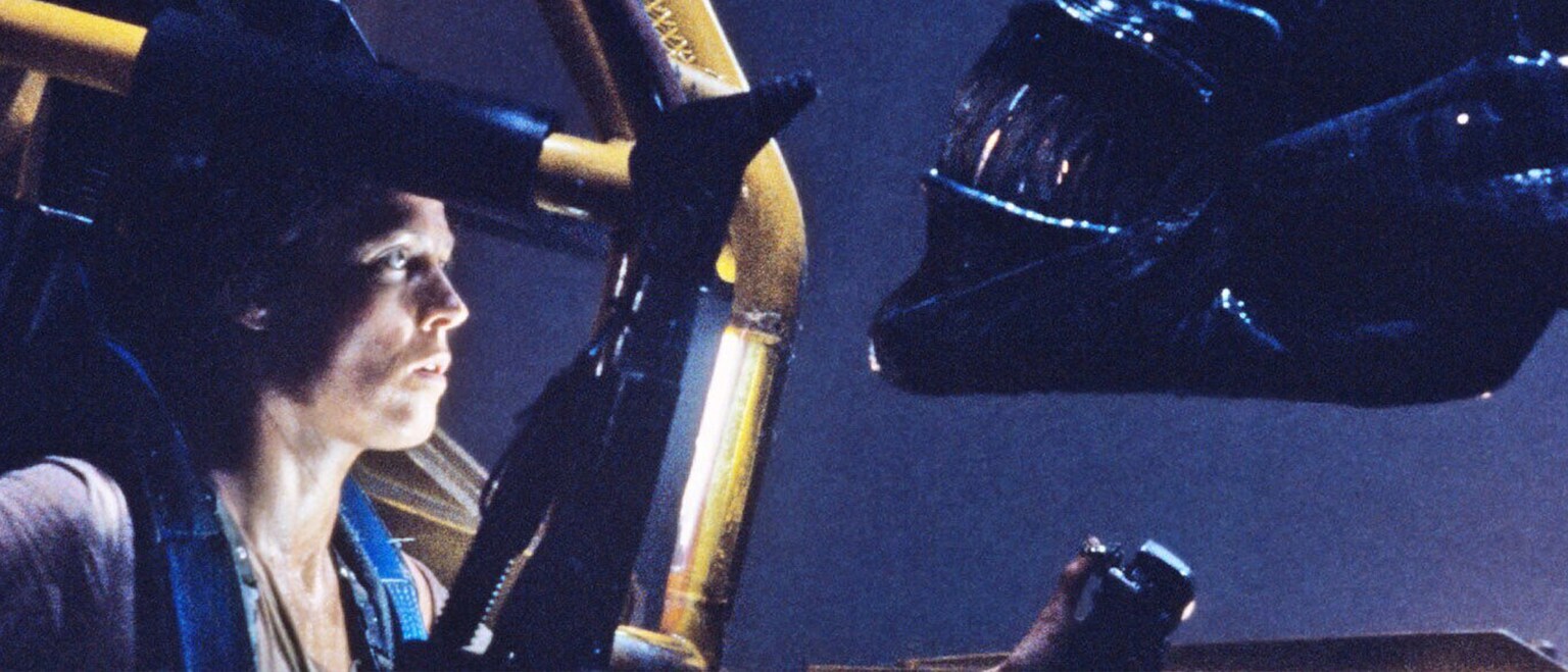 Image of Ripley (actor Sigourney Weaver) in the loader staring at the alien queen from the 20th Century Studios movie, "Aliens."
