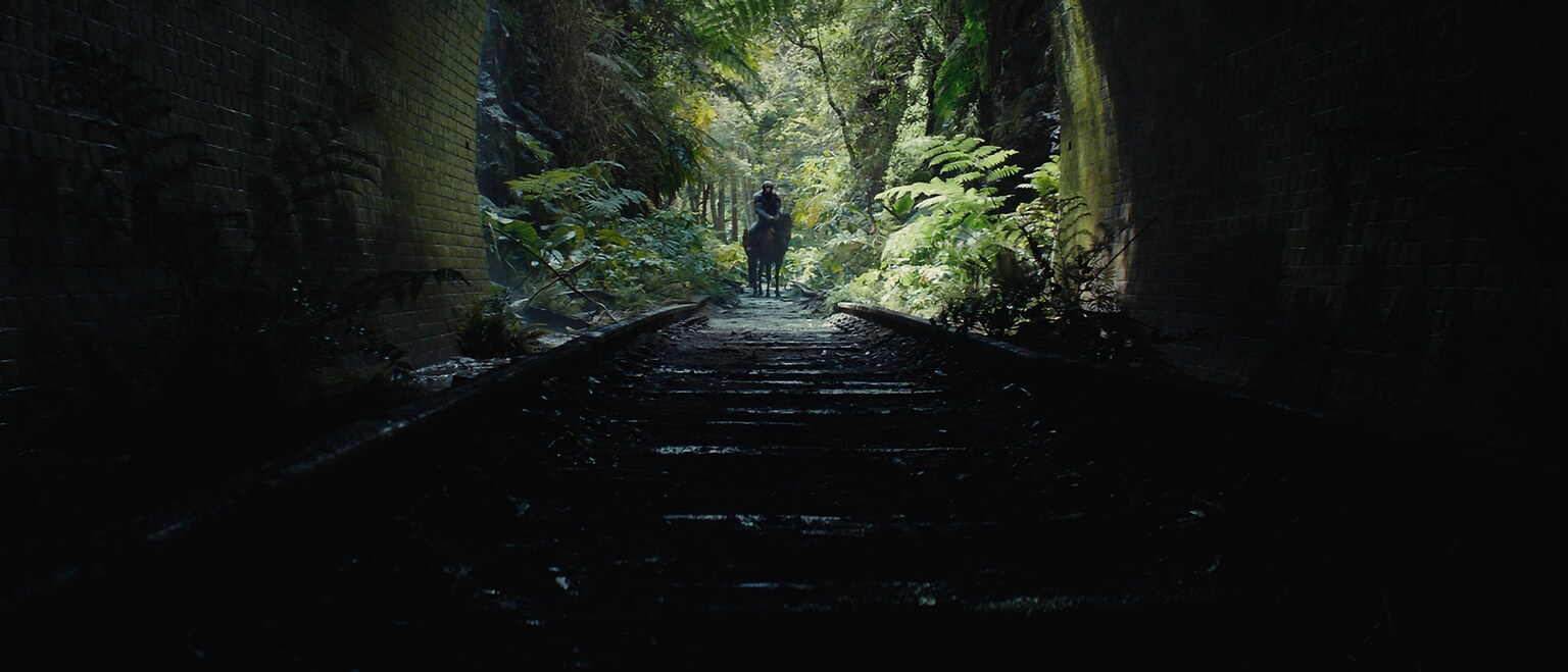 Noa (voiced by Owen Teague) on horse staring into a dark tunnel in 20th Century Studios' KINGDOM OF THE PLANET OF THE APES. Photo courtesy of 20th Century Studios. © 2023 20th Century Studios. All Rights Reserved.