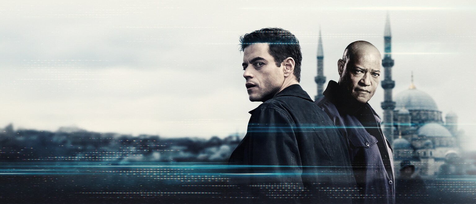 Image of Heller (Rami Malek) and Henderson (Laurence Fishburne) wearing dark jackets with concerned looks on their faces. From the 20th Century Studios movie, "The Amateur."