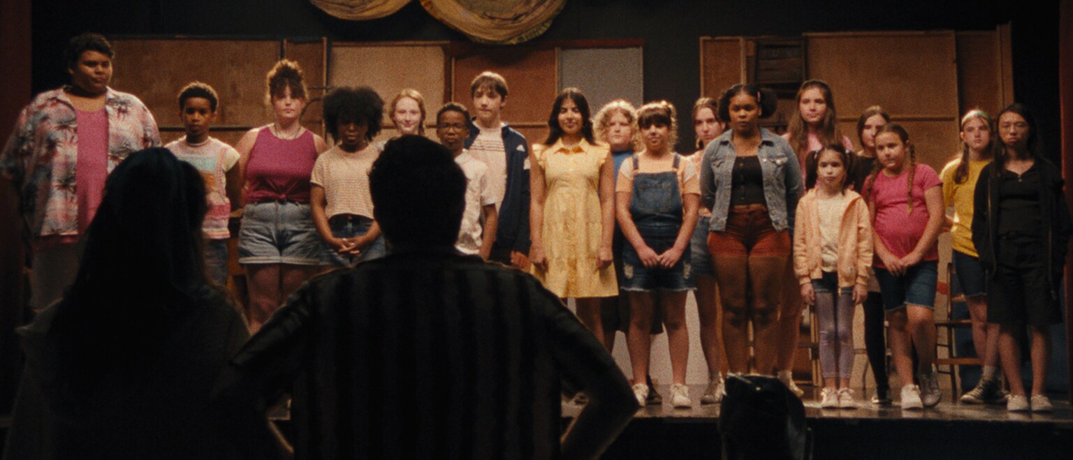 Image of a group of people on a stage from the Searchlight Pictures movie, "Theater Camp."