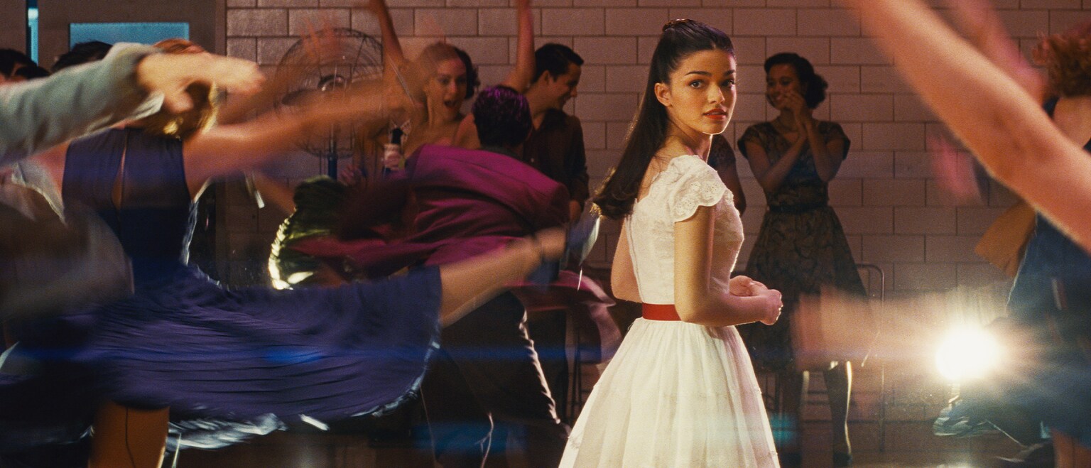 Actor Rachel Zegler looking over her shoulder on a dance floor from the 20th Century Studios movie "West Side Story".