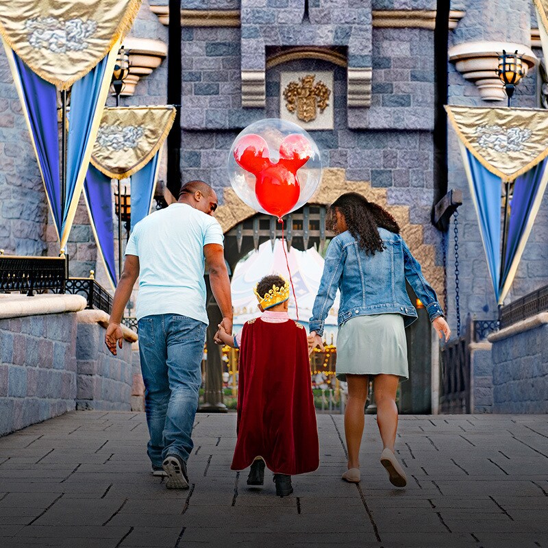 A family of three walks into the castle at Disneyland Resort.