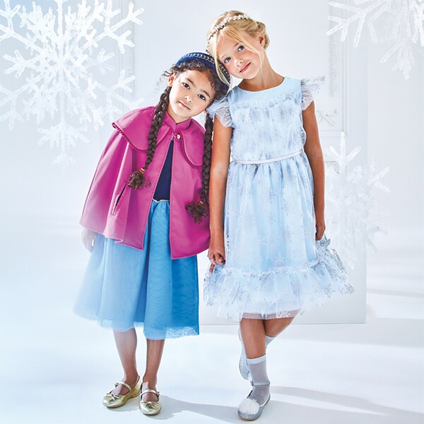 Two girls pose in Disney Frozen Collection by Janie & Jack dresess.