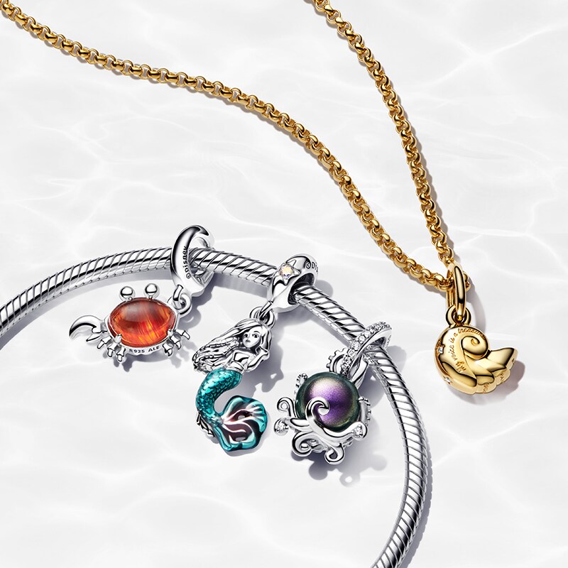 Image of a silver bracelet with three The Little Mermaid charms, and a gold necklace with a scallop shell pendant.