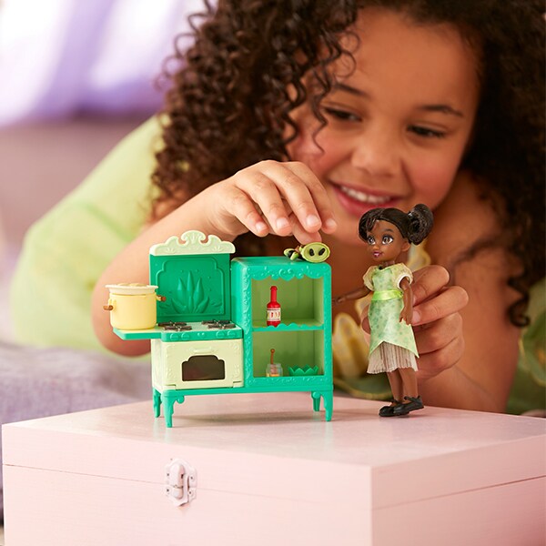 Photo of a girl playing with a Tiana doll and toy set.