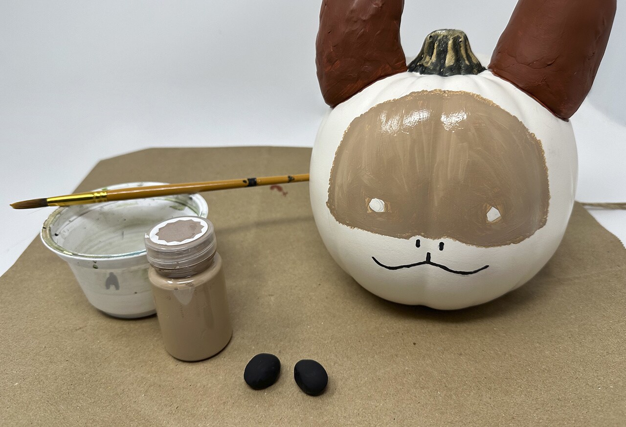 Paint the two eyes and the Loth-cat’s nose and mouth with the black acrylic paint.