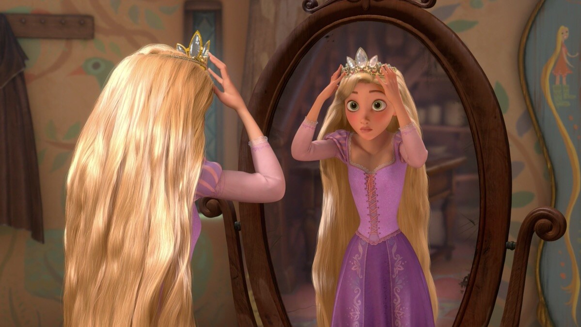 Rapunzel looking in the mirror at herself with a crown on in the movie "Tangled"