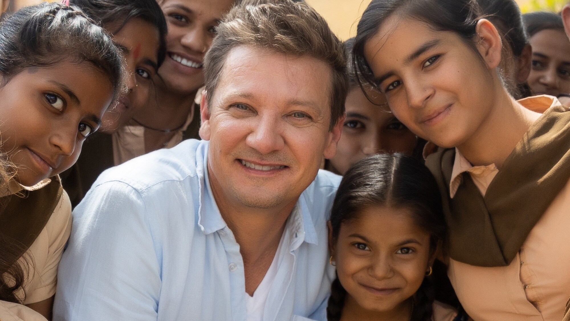 Jeremy Renner poses with children at the vehicle reveal in India as seen on Disney's RENNERVATIONS. (Disney/Mansi Midha)