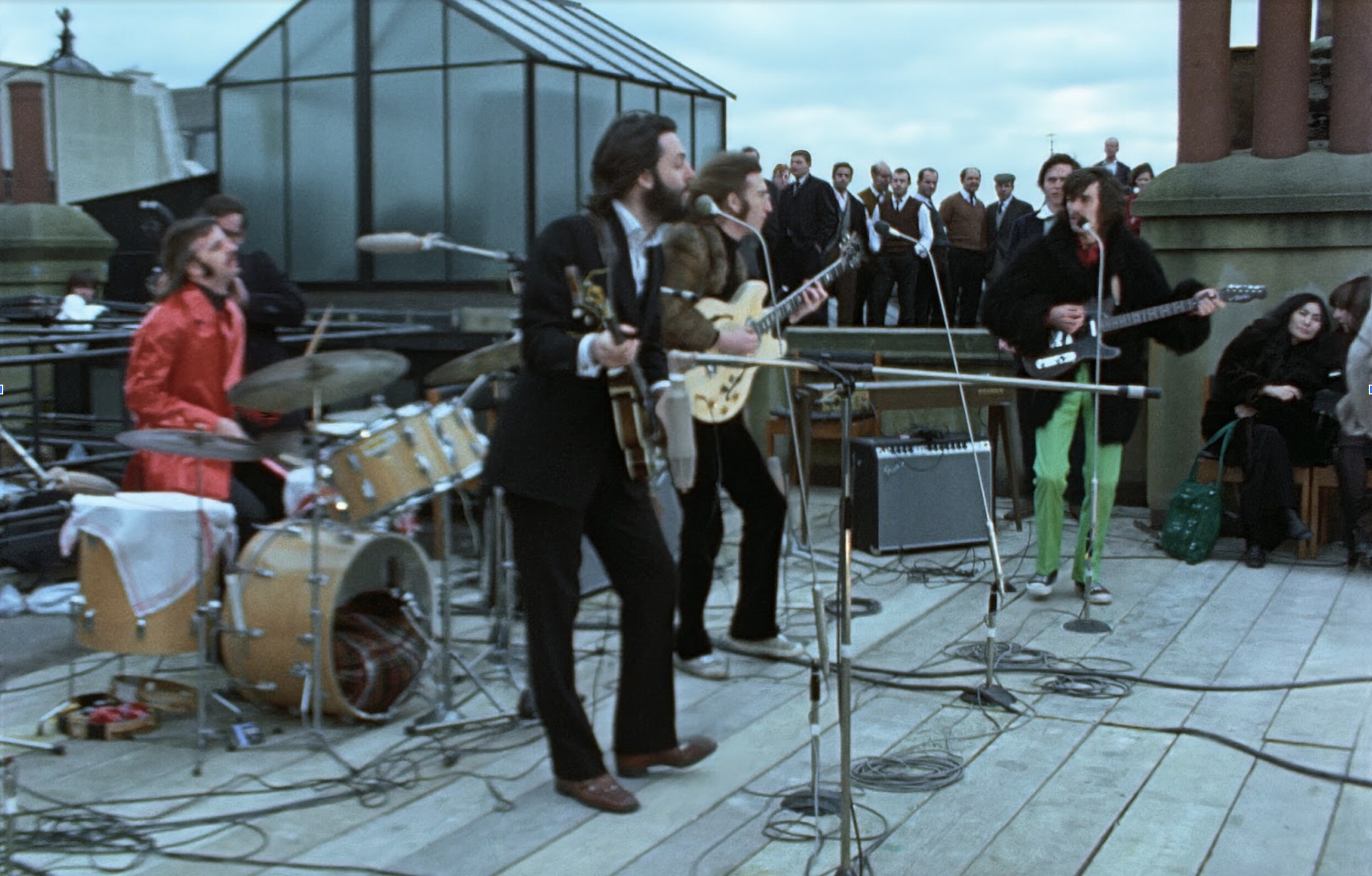 The Beatles perform on a rooftop in front of a small audience