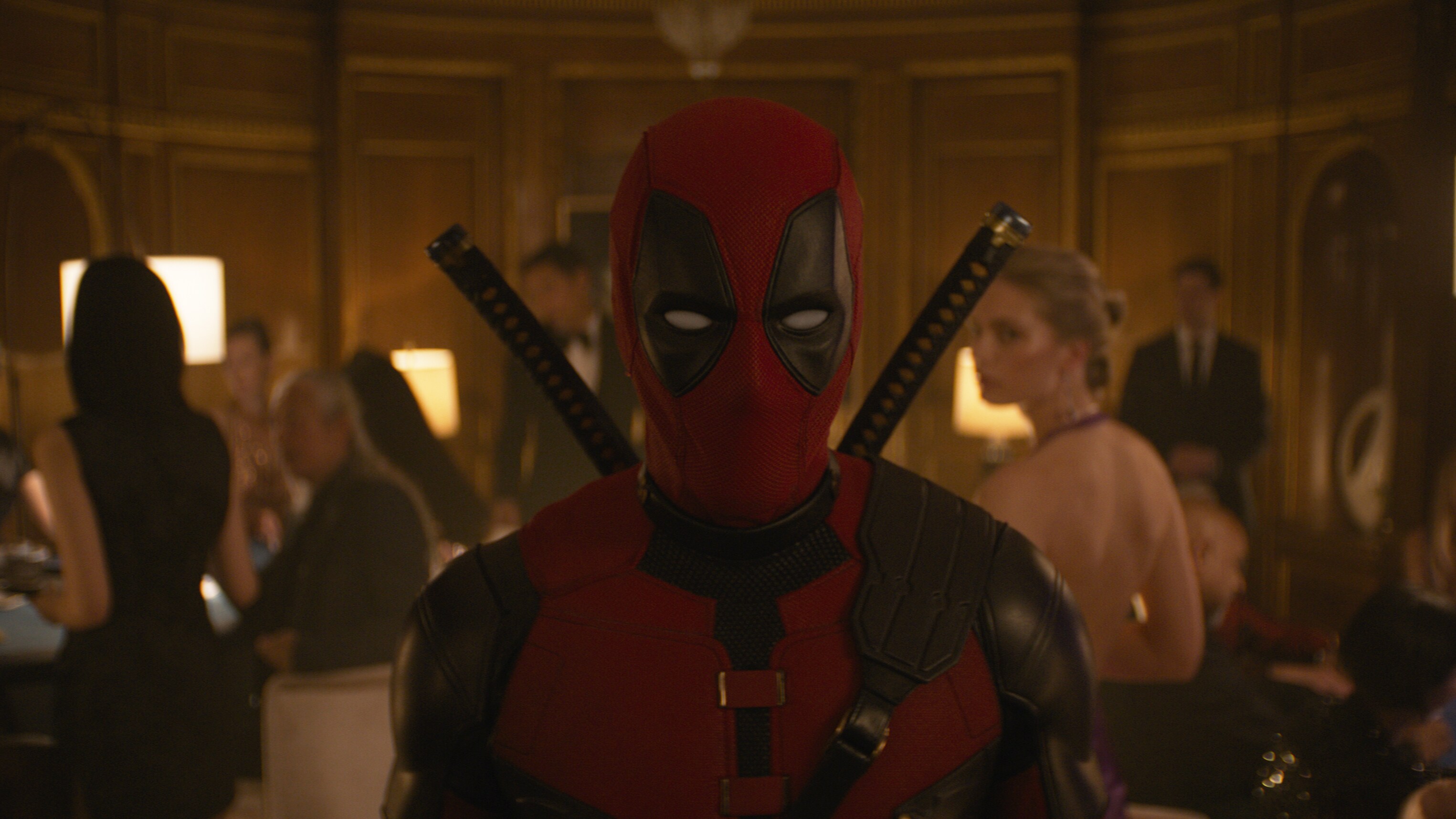 Deadpool aka Wade Wilson (actor Ryan Reynolds) standing inside a room full of party guests from the film "Marvel Studios' Deadpool & Wolverine".