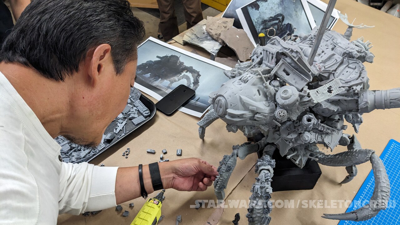 Production designer Doug Chiang glues “junk” onto the Mama Crab model.