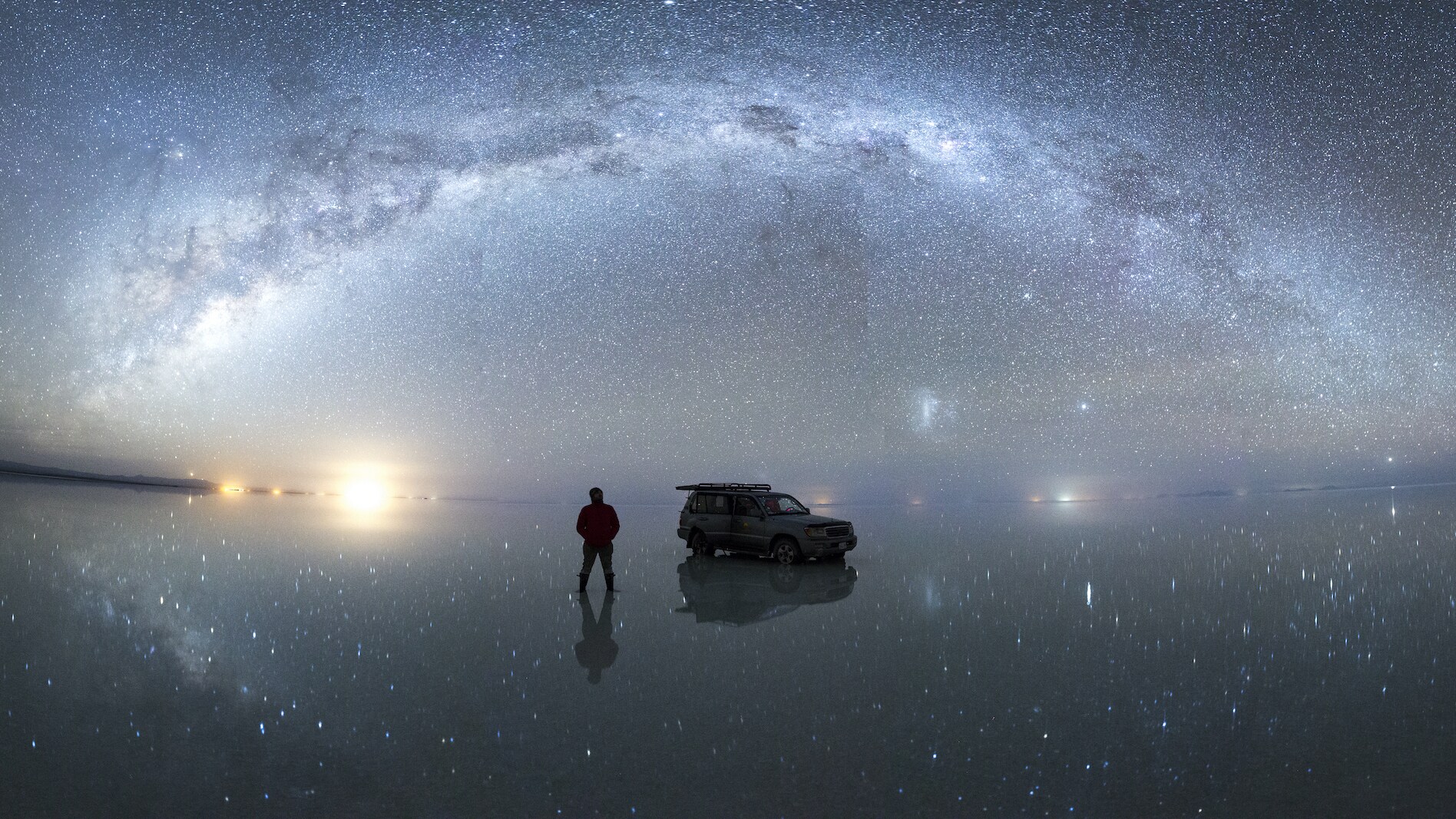 Crew member standing under the milky way, as it's reflected in the flood waters of the salar, after seasonal rains transform the salt flats into the largest mirror on the planet.  (National Geographic/Freddie Claire)