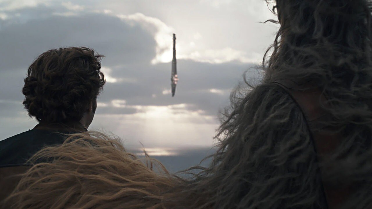 Chewbacca pats Han Solo on the back while they look out on the ocean.