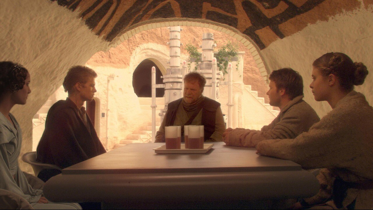 Aunt Beru, Owen Lars, Anakin, and Padme sit around a table