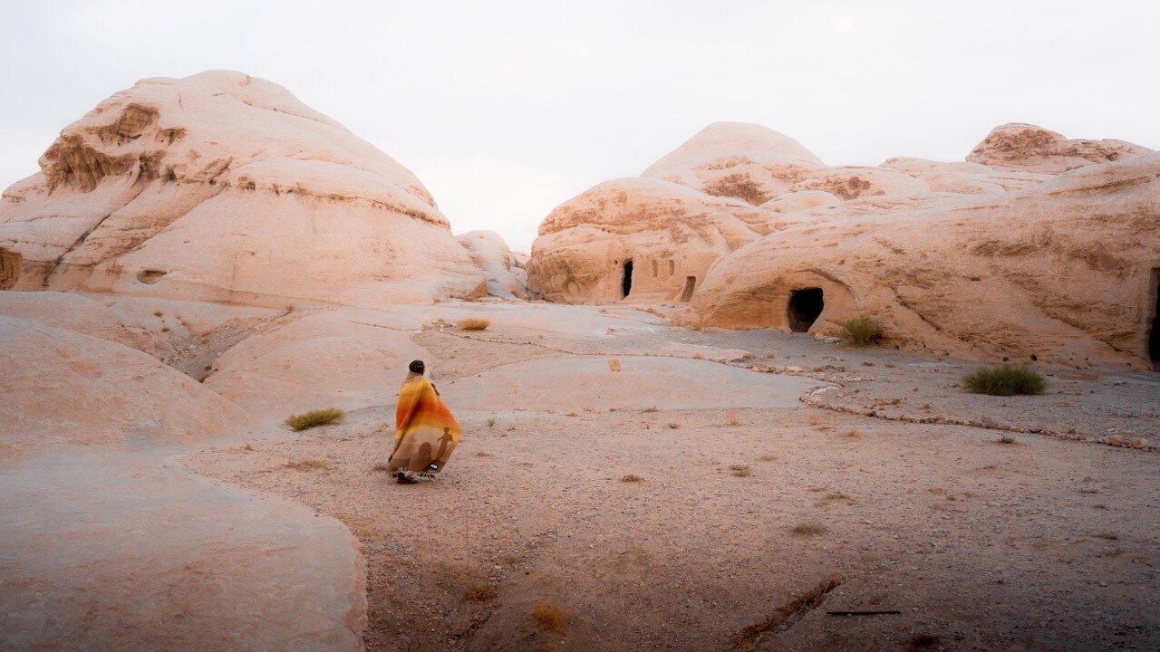 Woman in orange blanket overlooking desert