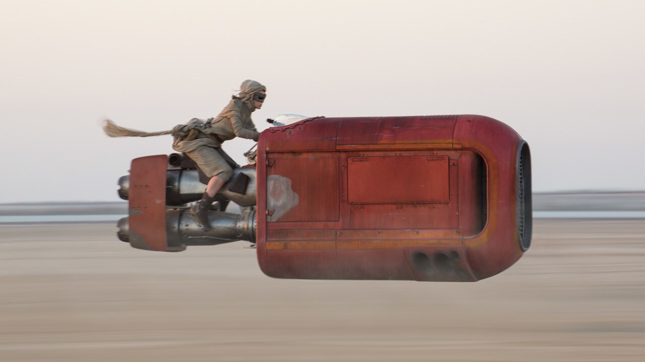 Rey pilots her speeder through the Jakku desert in Star Wars: The Force Awakens.