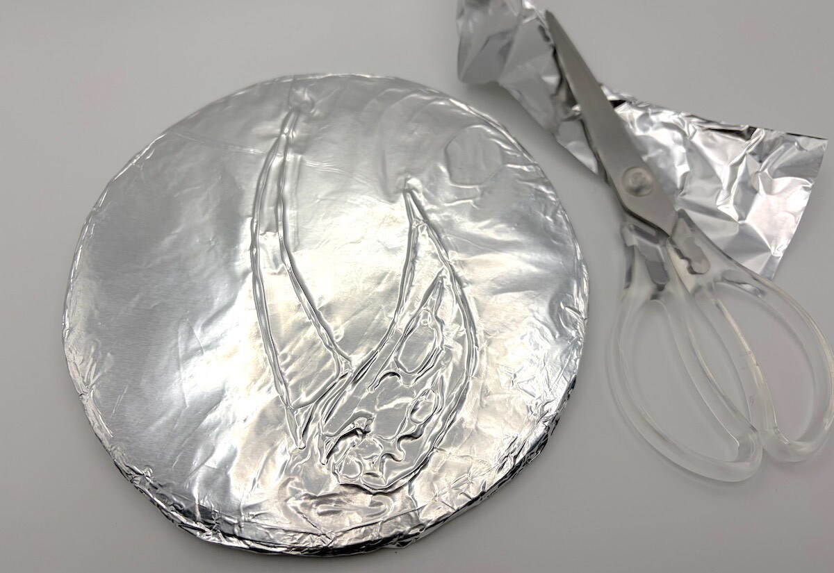 Cut a piece of foil slightly bigger than the cardboard circle.