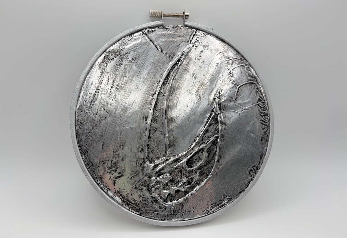 Gently press the dry foil circle into the silver hoop, loosening and tightening it as needed.