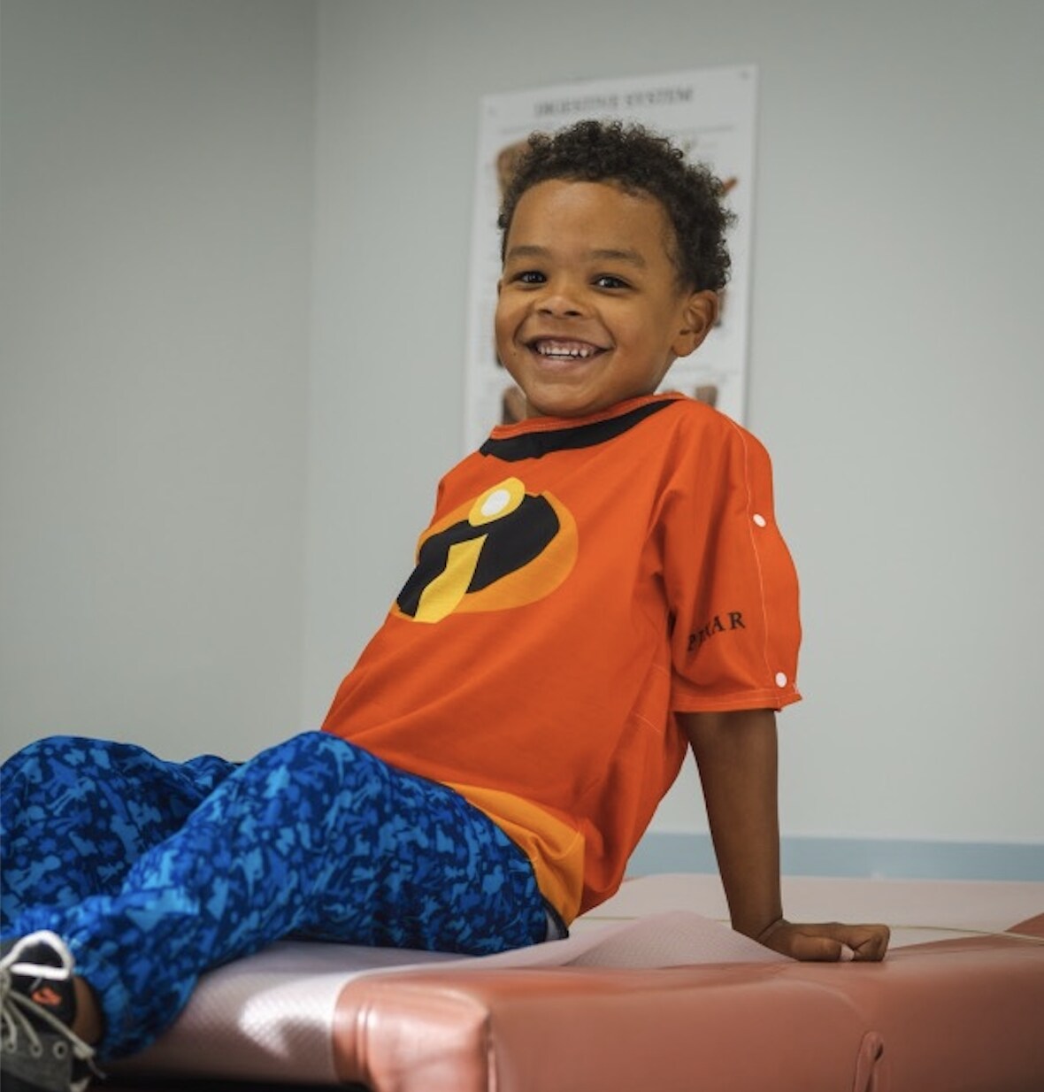 A boy smiles in his "Incredibles"-inspired Pixar-Starlight hospital gown.
