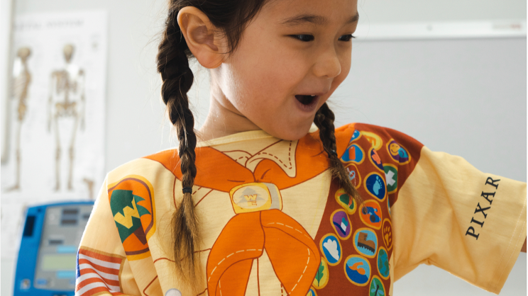 Girl smiles in "Up"-inspired Pixar and Starlight hospital gowns.