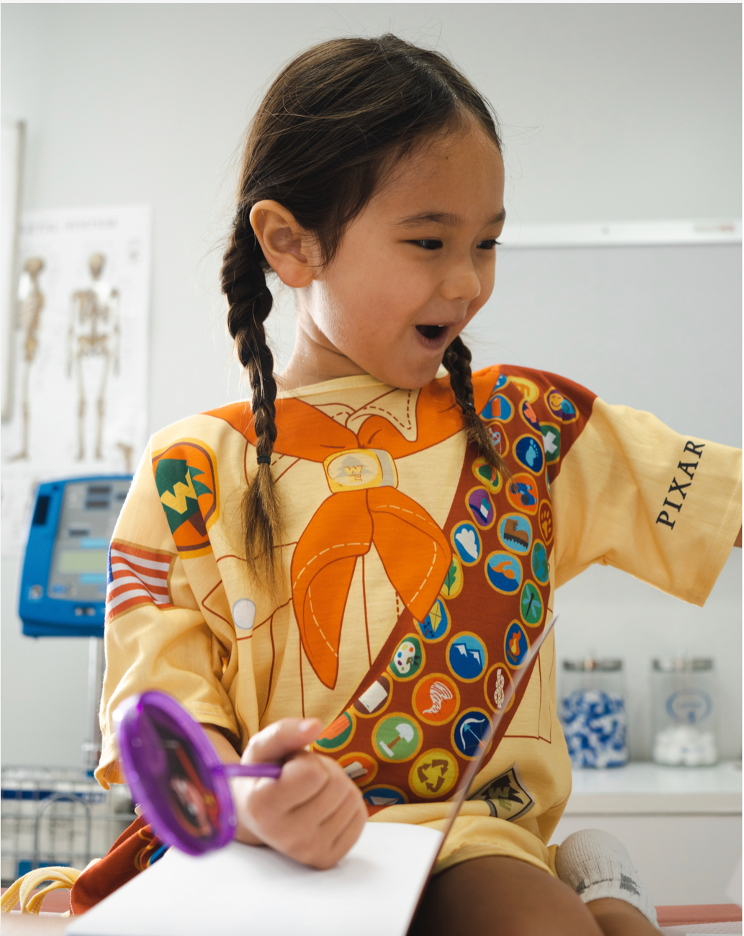 A girl smiles in her "Up"-inspired Pixar-Starlight hospital gown.