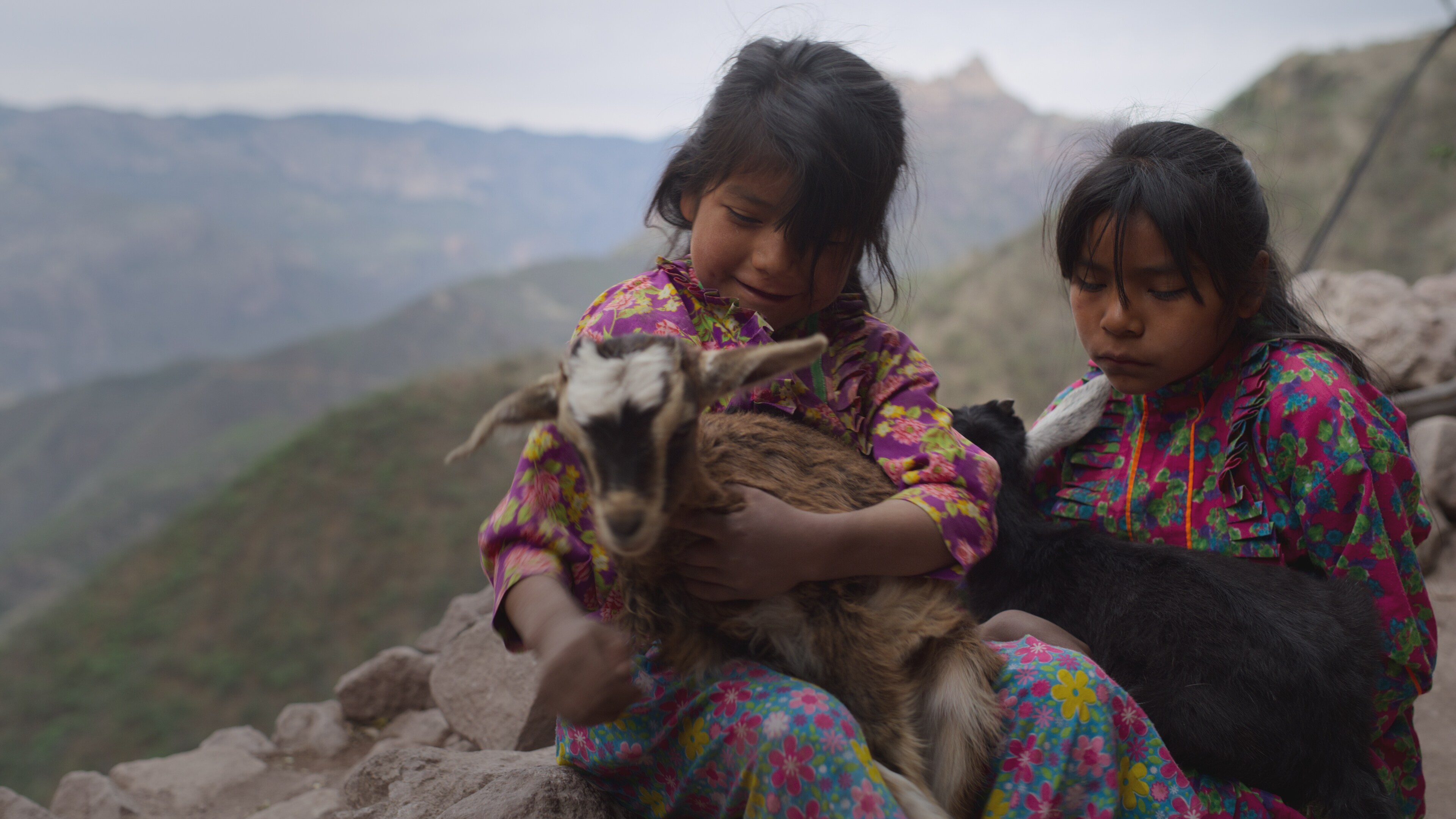 Sofia and Imelda (Catalina's daughters) sit with goats. (National Geographic for Disney+)