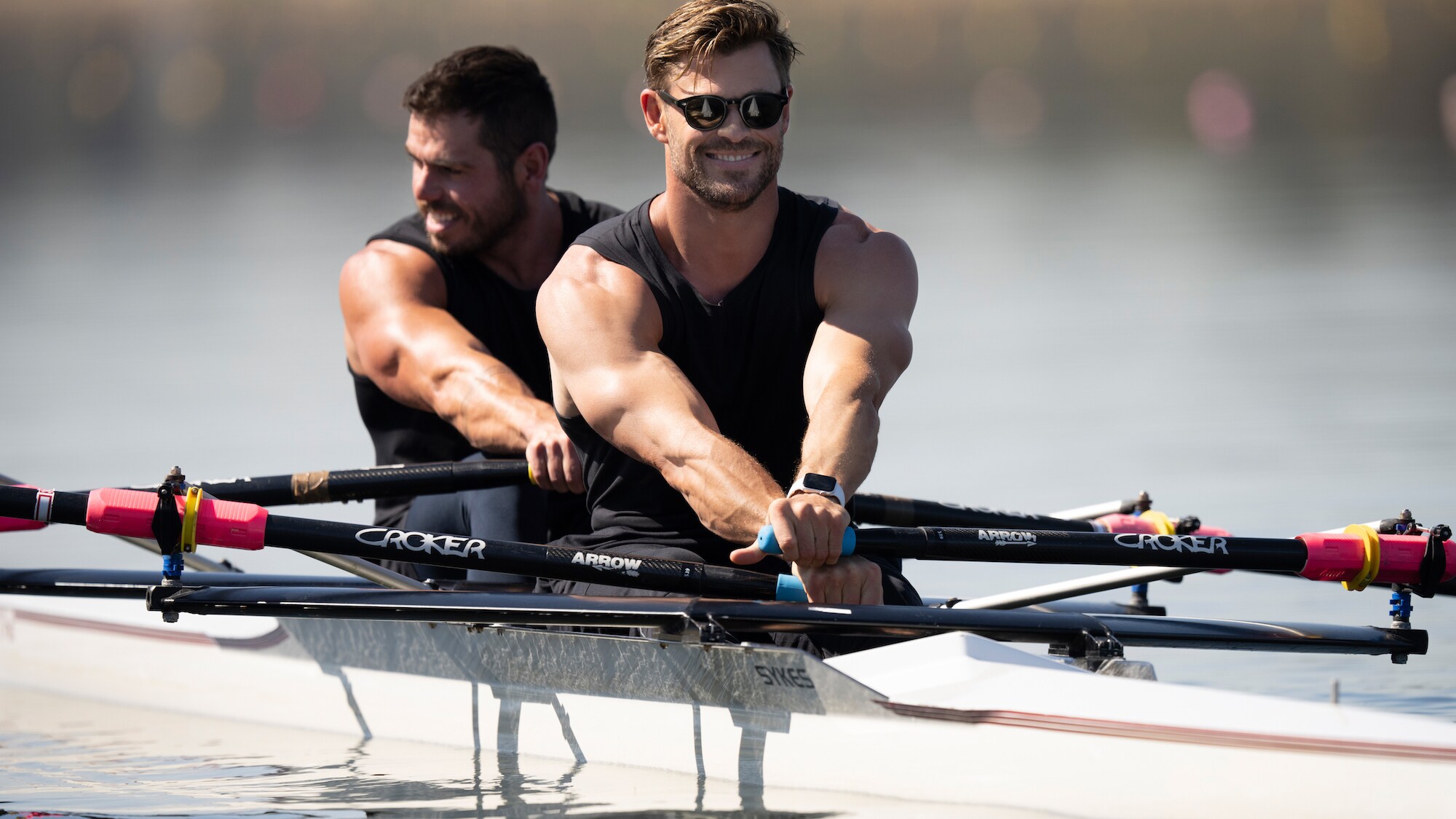 Chris Hemsworth smiles as he rows a boat. (National Geographic for Disney+/Craig Parry)