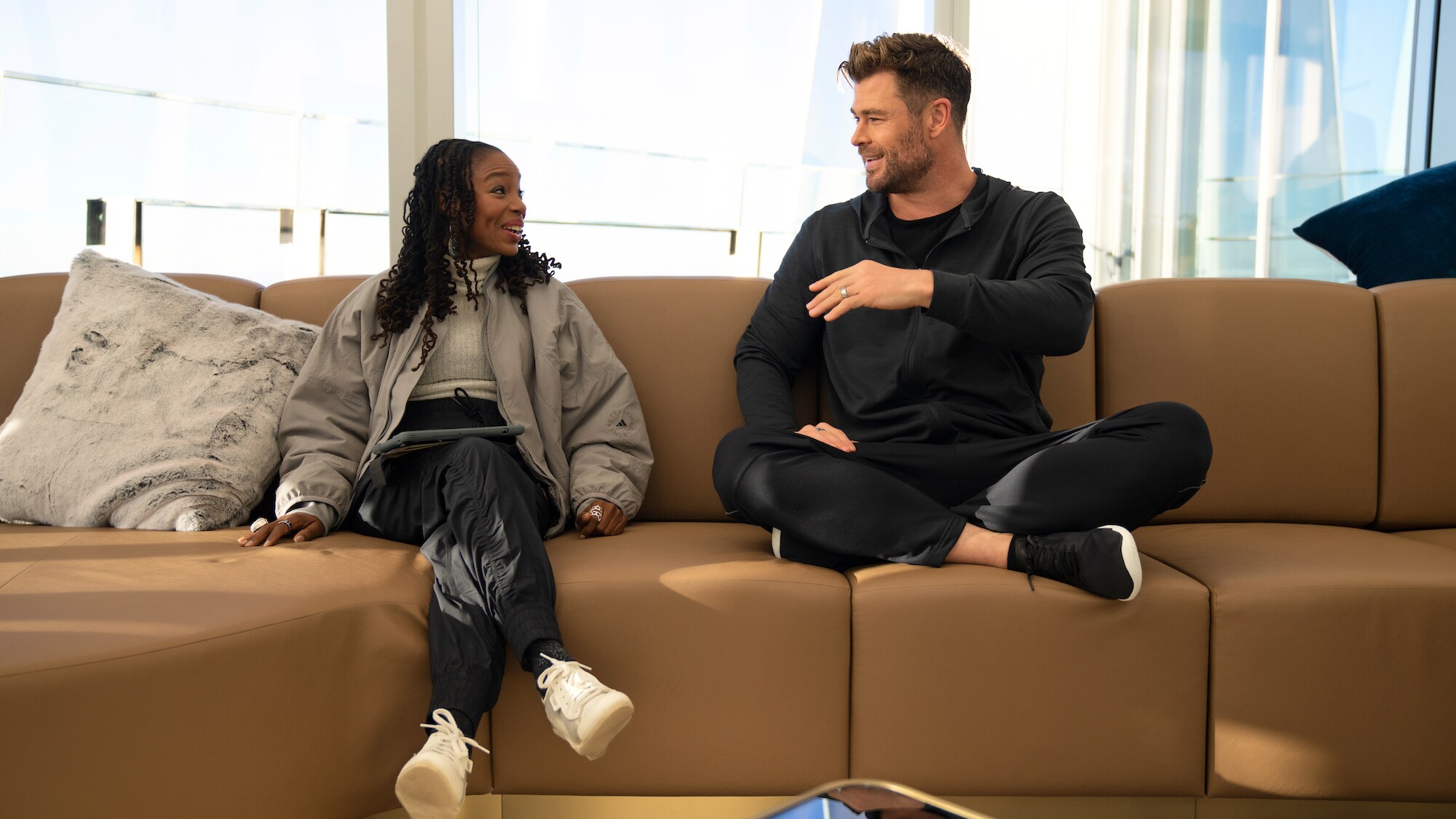 Dr. Modupe Akinola and Chris Hemsworth talk on the couch before Chris attempts an epic crane walk.(National Geographic for Disney+/Craig Parry)