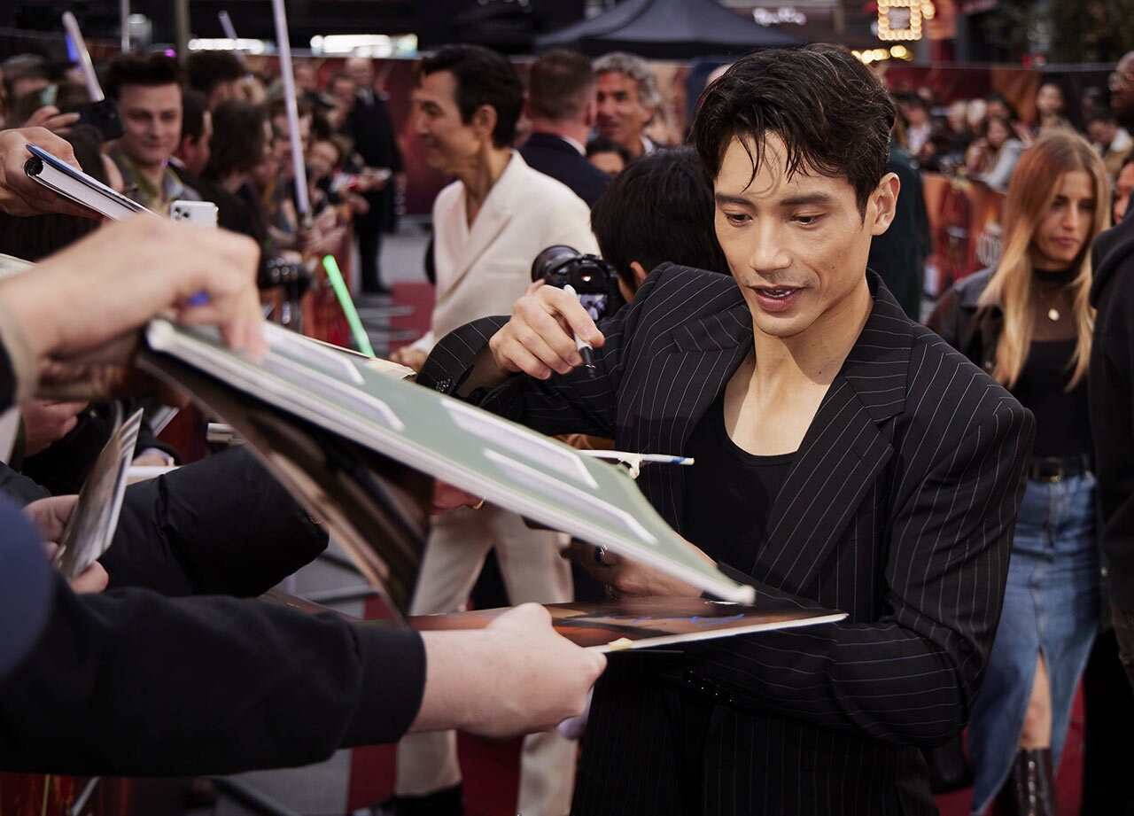 Manny Jacinto signs his autograph for fans at The Acolyte red carpet.