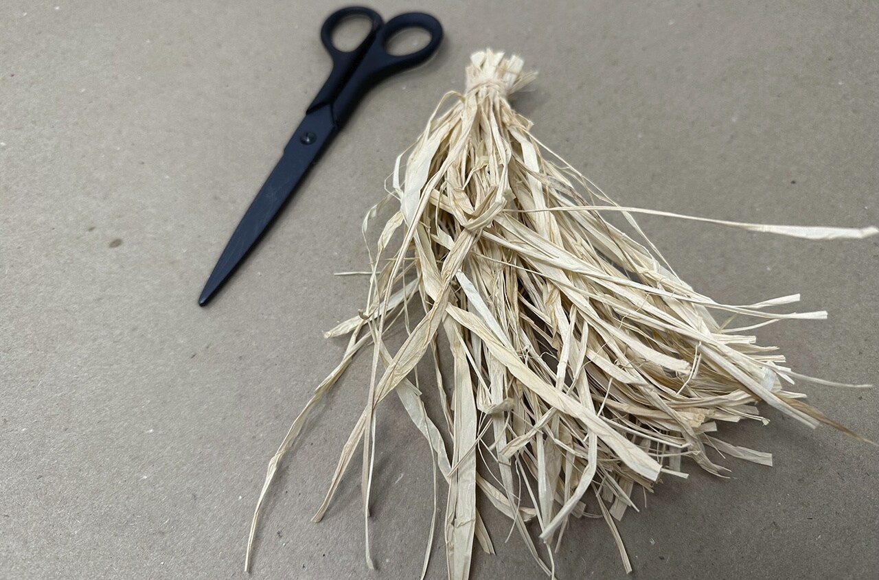 Step 7: Gather a large bunch of raffia and tie a piece of straw around the top. Trim the ends and set the large bunch aside.