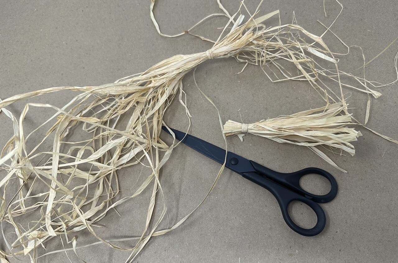 Step 12: Next, gather two small bundles of raffia to make Lula’s ears. Tie them on one end, then trim both ends of the ears so that they are about 3.5 inches in length.