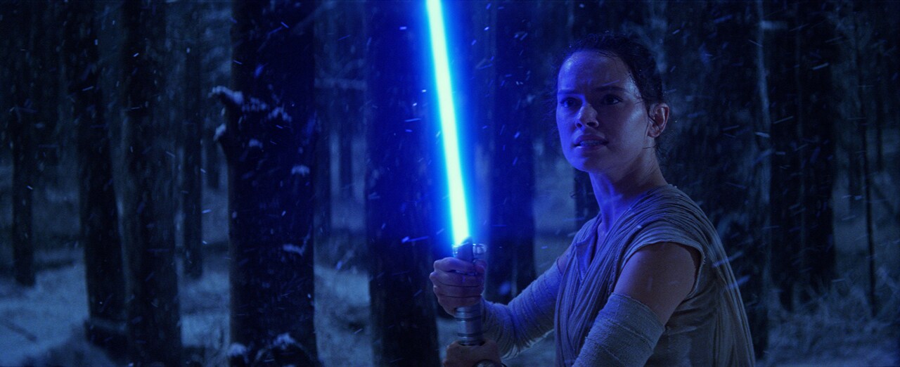 Rey ignites the lightsaber to fight Kylo Ren.