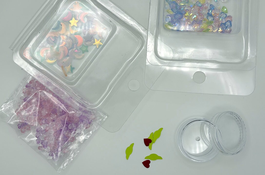 Beads, tiny red hearts, and the Grogu shapes inside the clear cosmetic container.