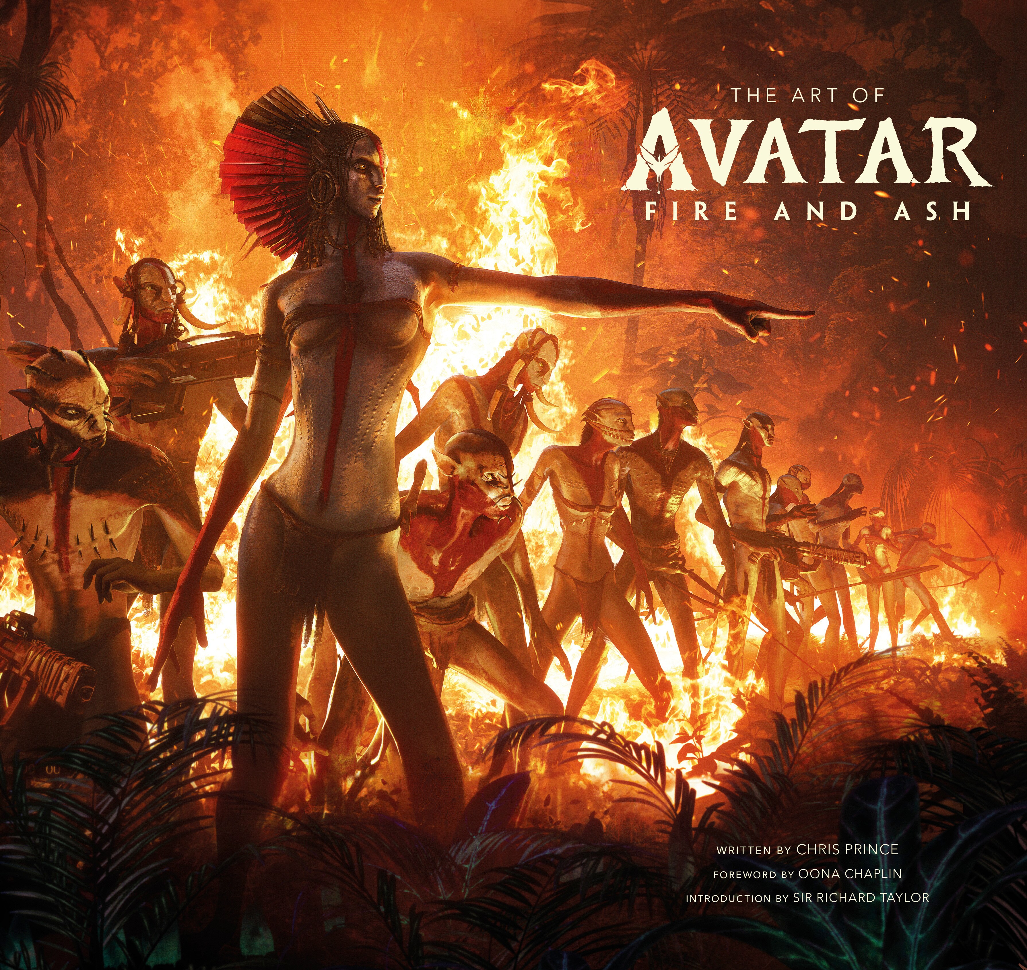 Image of Varang (actor Oona Chaplin) standing and pointing while in front of several Na'vi. There is a large fire burning in the background.