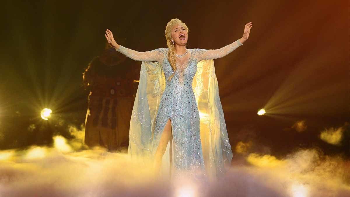 Elsa performer signing with her arms up and stage fog covering her feet