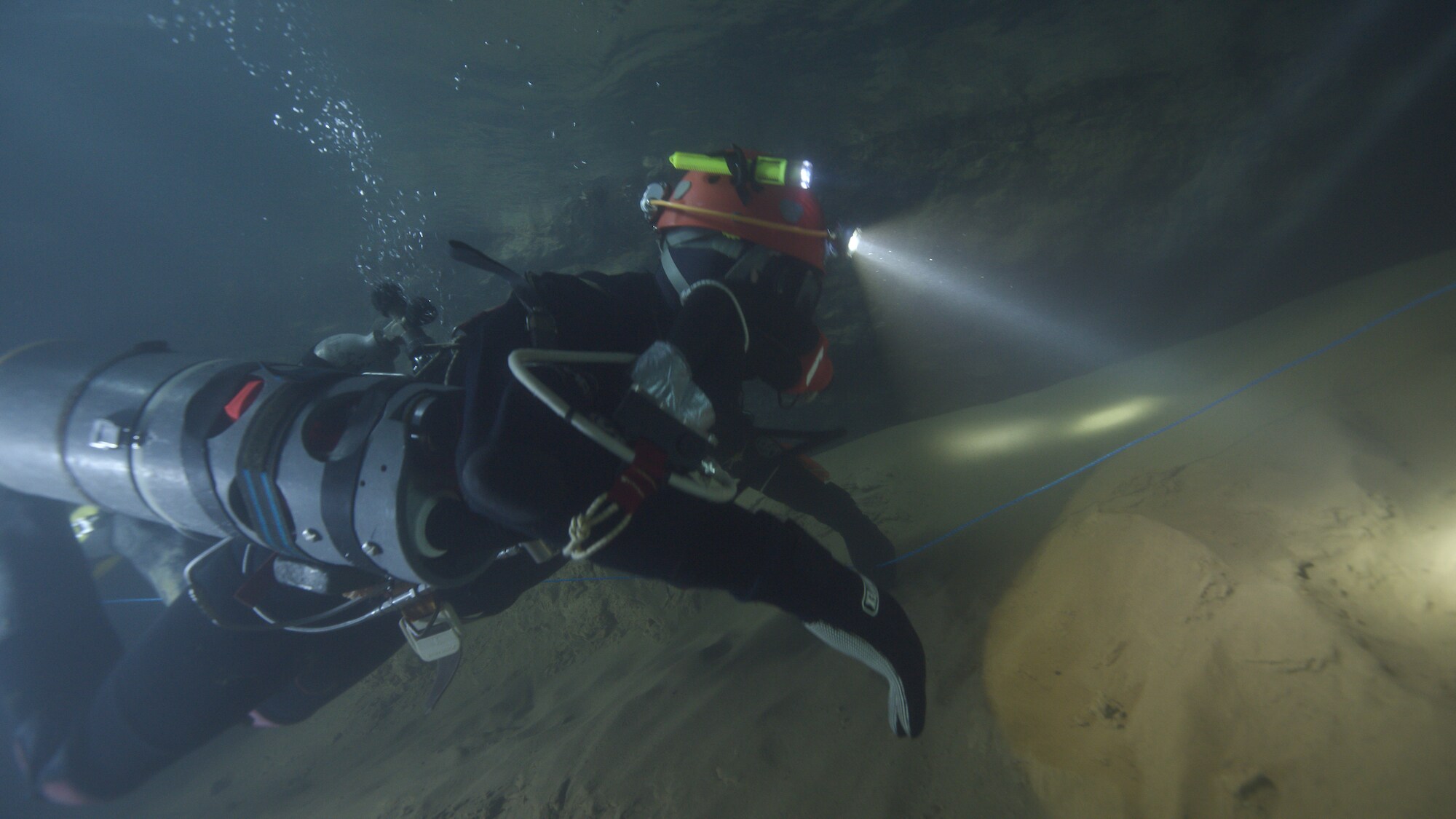 Diver in cave with headlamp.  THE RESCUE chronicles the 2018 rescue of 12 Thai boys and their soccer coach, trapped deep inside a flooded cave. E. Chai Vasarhelyi and Jimmy Chin reveal the perilous world of cave diving, bravery of the rescuers, and dedication of a community that made great sacrifices to save these young boys. (Credit: National Geographic)