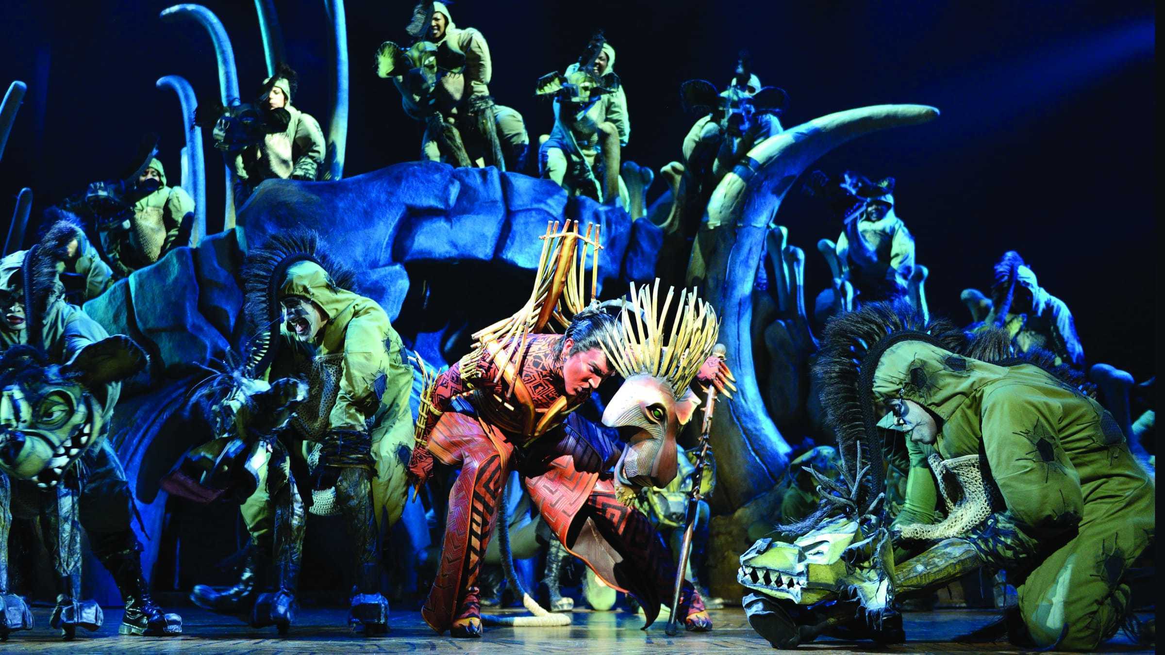 Scar character in costume with cast members in Hyena costumes.